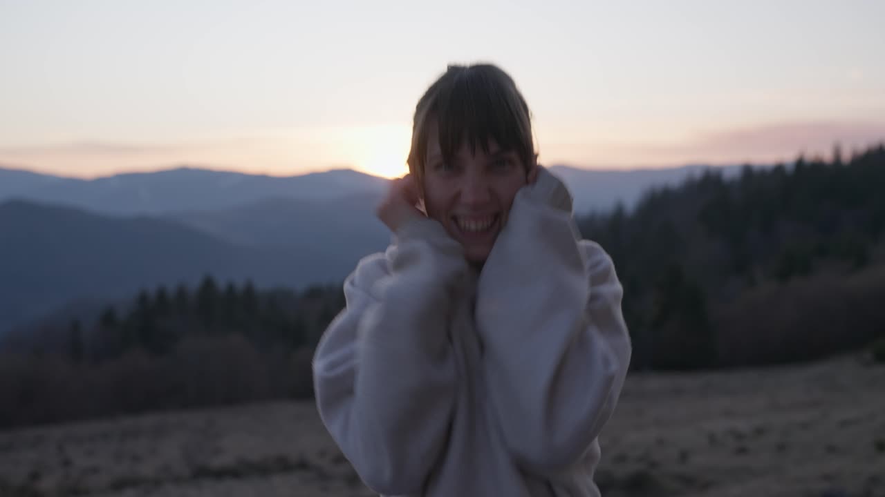 Portrait of a smiling woman in mountains at sunset