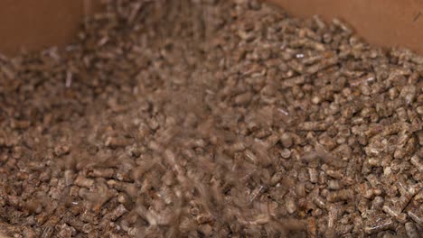 wood pellets falling and piling up in a wooden chest, for use as an eco-friendly renewable organic biofuel or mulch in the garden