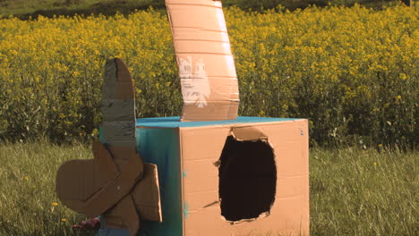 niño feliz subiendo a un avión de juguete hecho a sí mismo en un campo durante la puesta de sol