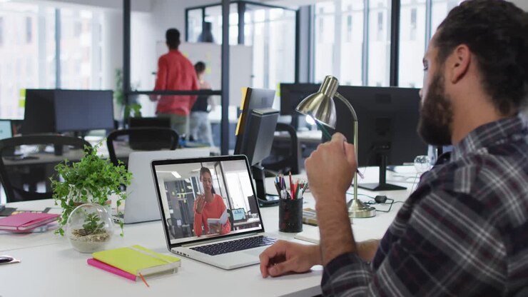 Middle eastern man having a video call with female colleague on laptop at office