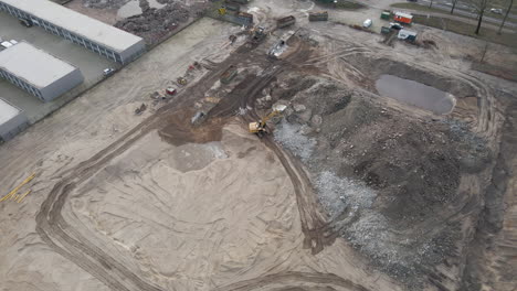 pluma abajo de la excavadora recogiendo escombros del edificio demolido en el sitio de construcción