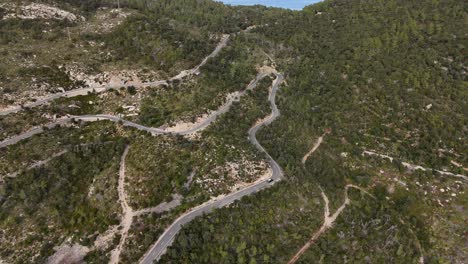 drone shot of driving cars on the winding road in the esporles valley on the island village of mallorca in the serra de tramuntana, spain