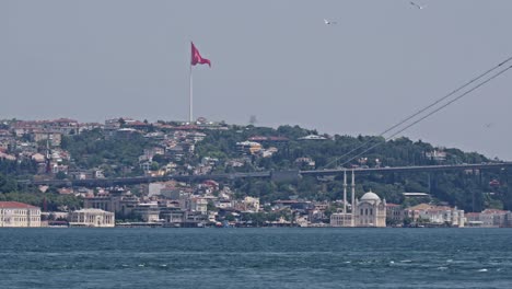 turkish flag on hillside waving in breeze, view over bosphorus strait and bridge