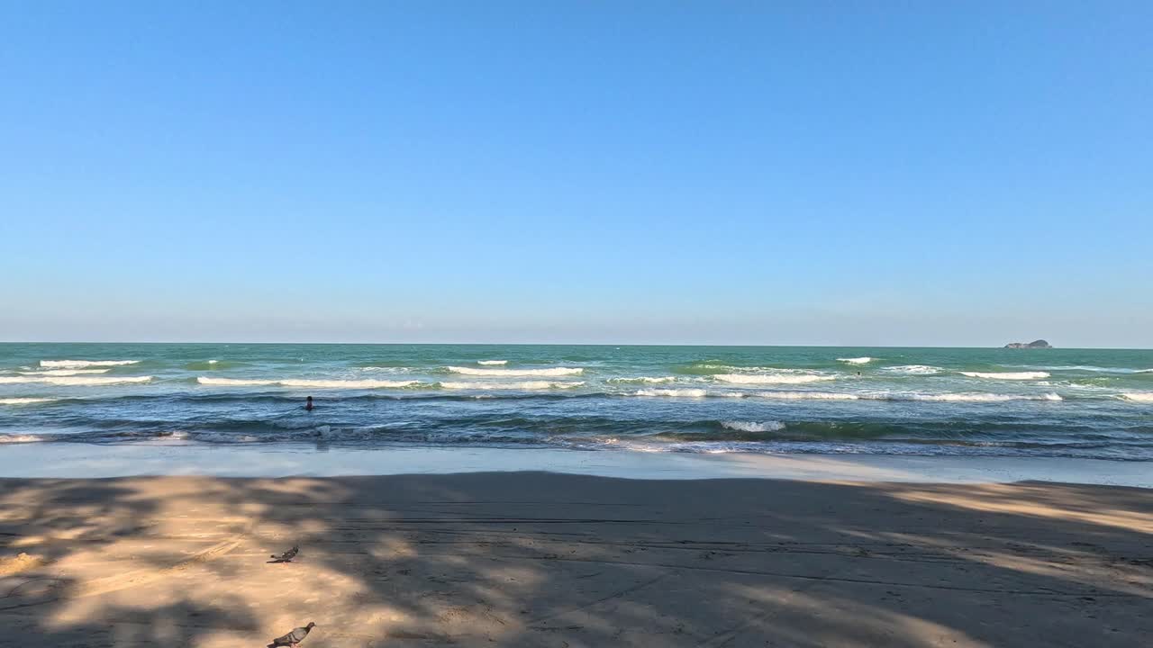 조용한 파도가 모래 해변에 굴러오고