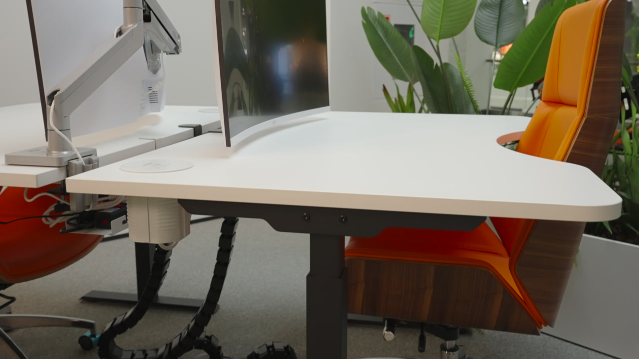 Curved Monitor Setup Beside Orange Chair, Articulated Arm Mount, White Desk Surface, Tropical Foliage. Creative