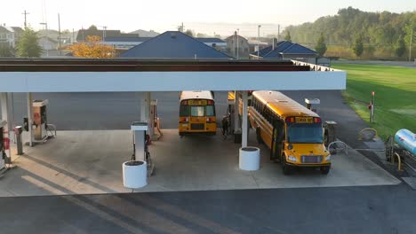 autobuses escolares amarillos repostando en la gasolinera de una pequeña ciudad en américa después de conducir la ruta con los estudiantes