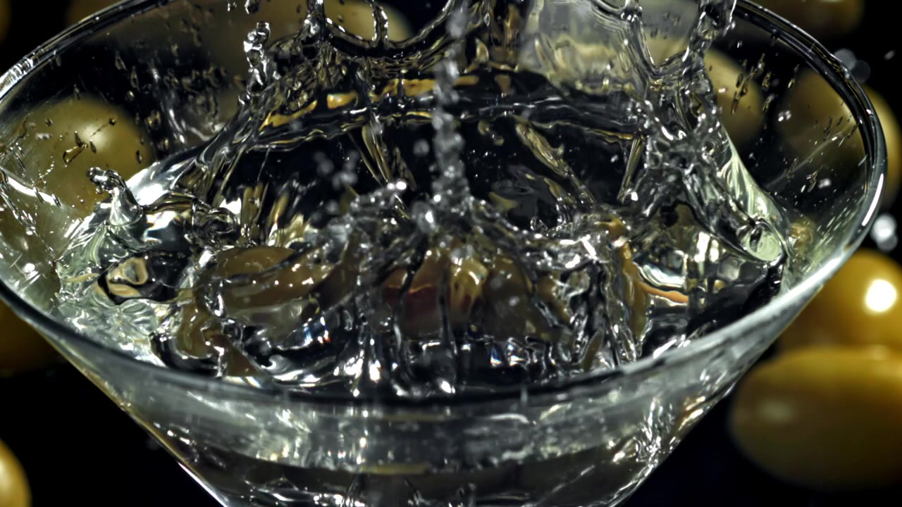 Olive verdi che schizzano in un cocktail Martini al rallentatore