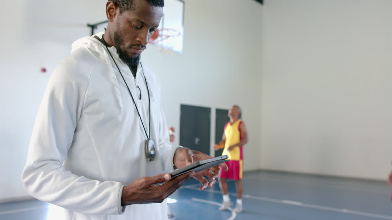 Allenatore afroamericano esamina i dati su un tablet in una struttura sportiva
