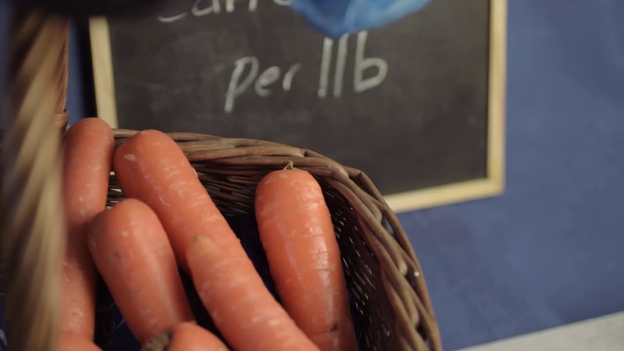 Hand with hygiene blue gloves putting carrots in a plastic bag
