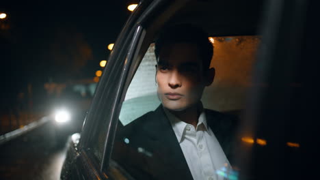 rich businessman riding car at night closeup. elegant passenger looking outside