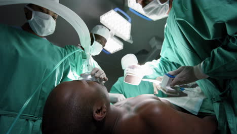 diverse surgeons using defibrillator on patient in operating theatre at hospital, slow motion