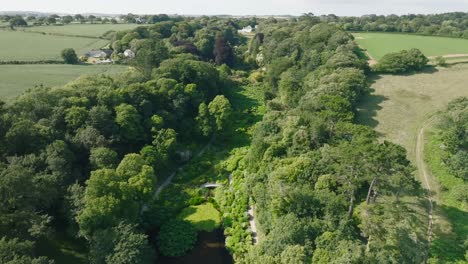 tree lined tropical garden paradise valley with white mansion at valley head on summer day.