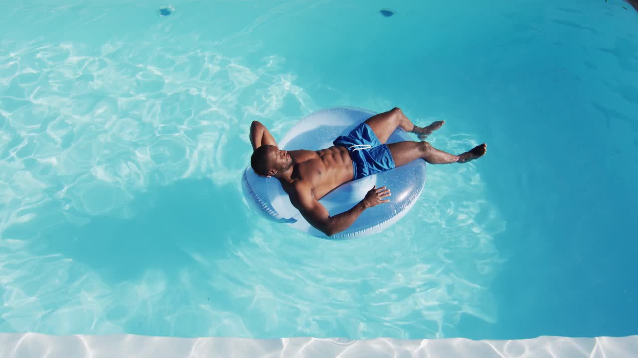 Mixed race man having fun sunbathing on inflatable in swimming pool