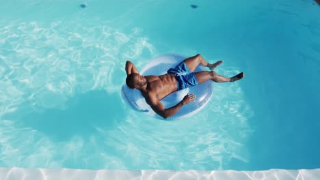 mixed race man having fun sunbathing on inflatable in swimming pool