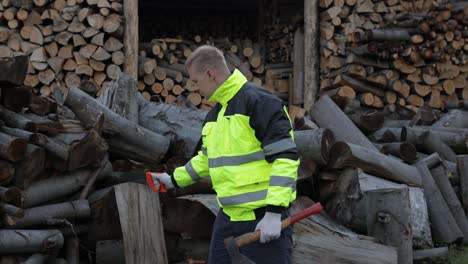 lumberjack in reflective jacket. man woodcutter holds small axe and saw on his hands. firewood