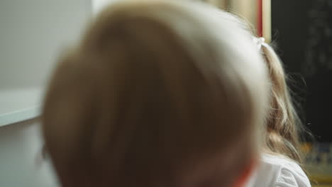 toddler draws circles around eyes of sister face with red pencil