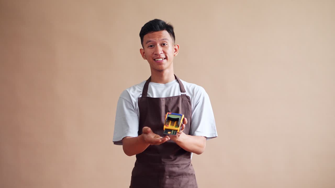 Young barista proudly presents machine EDC offering convenience in payment with warm smile