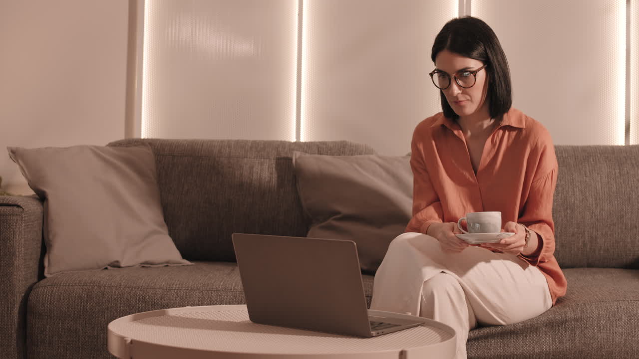 mujer bebiendo té y usando laptop