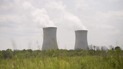 nuclear power plant on a warm cloudy day with steam rising - handheld shot