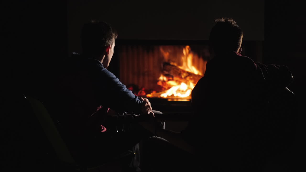 dos tipos tocando la guitarra junto a la chimenea