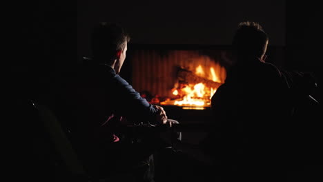 two guys playing the guitar by the fireplace