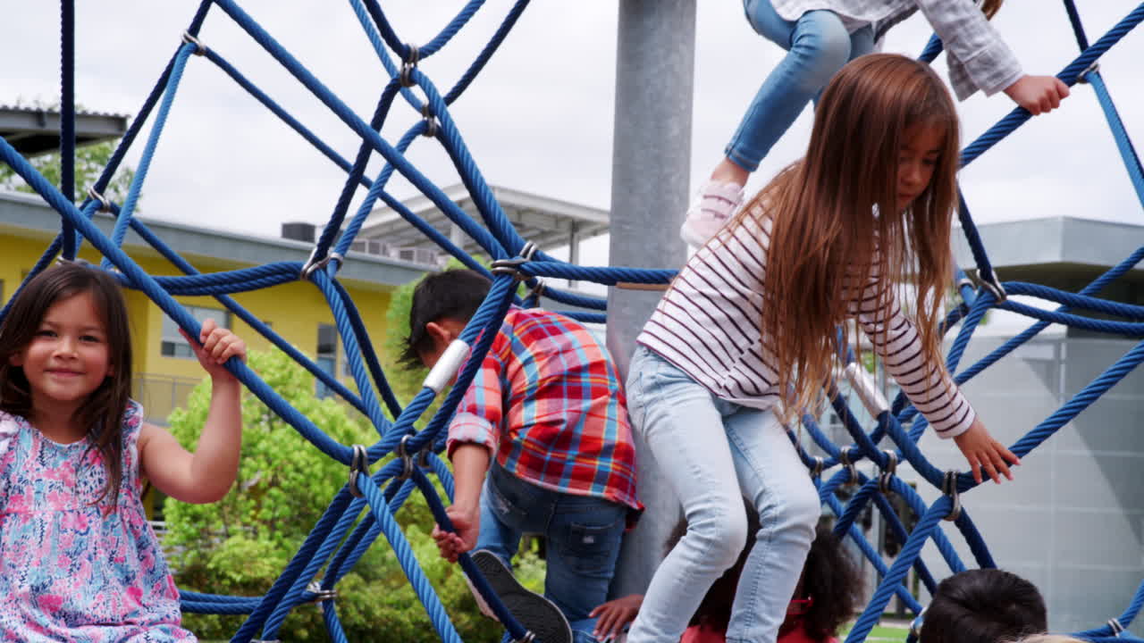 niños de escuela primaria jugando en la red de escalada en el patio de recreo