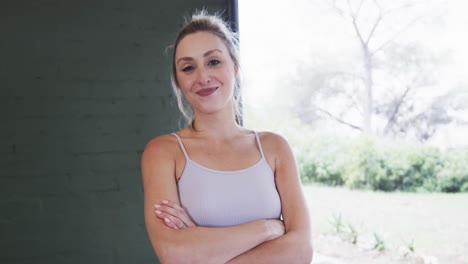 Confident-caucasian-young-woman-with-arms-crossed-standing-in-yoga-studio,-copy-space