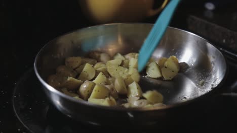 moving the skillet and turning the slices of potatoes using a spatula - close up shot