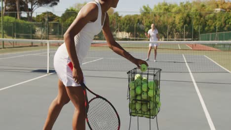 Video-Einer-Afroamerikanischen-Tennisspielerin,-Die-Einen-Schläger-Hält-Und-Mit-Einer-Freundin-Trainiert