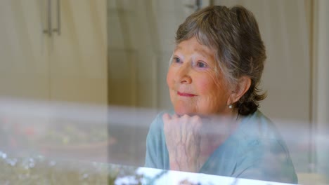 smiling senior woman looking through the window 4k