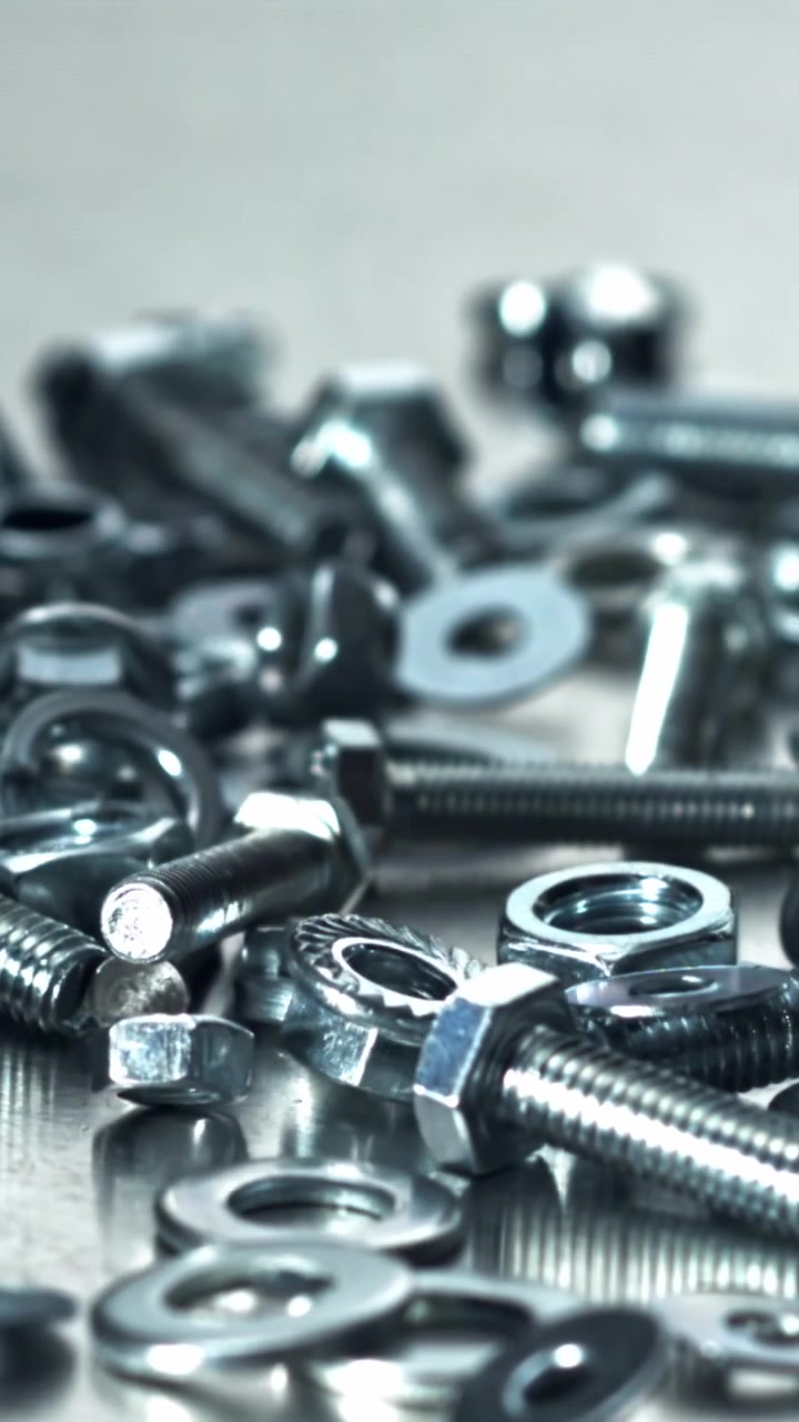 Vari elementi di fissaggio metallici che cadono e si disperdono su una superficie
