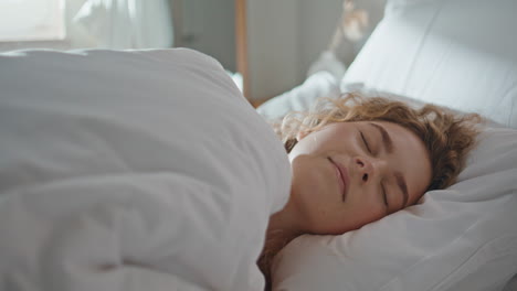 awake girl turning smartphone alarm off closeup. calm lady sleeping cozy pillow