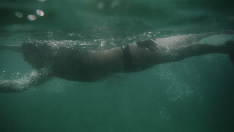 slow-motion underwater view of a swimmer in sydney, australia, with sunlight filtering through the clear water