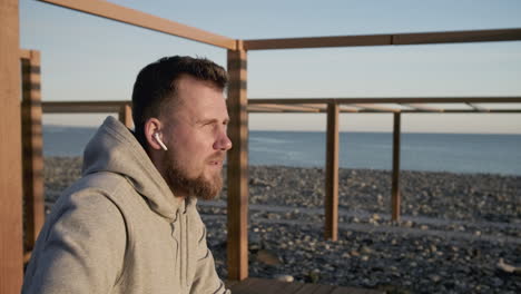 man listening to music on a beach