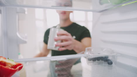 Joven-Mirando-Dentro-Del-Refrigerador-Vacío-Excepto-Por-La-Lata-Abierta-En-El-Estante