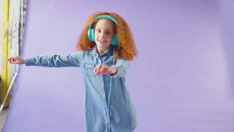 Foto-De-Estudio-De-Una-Chica-Con-Auriculares-Y-Bailando-Sobre-Fondo-Morado