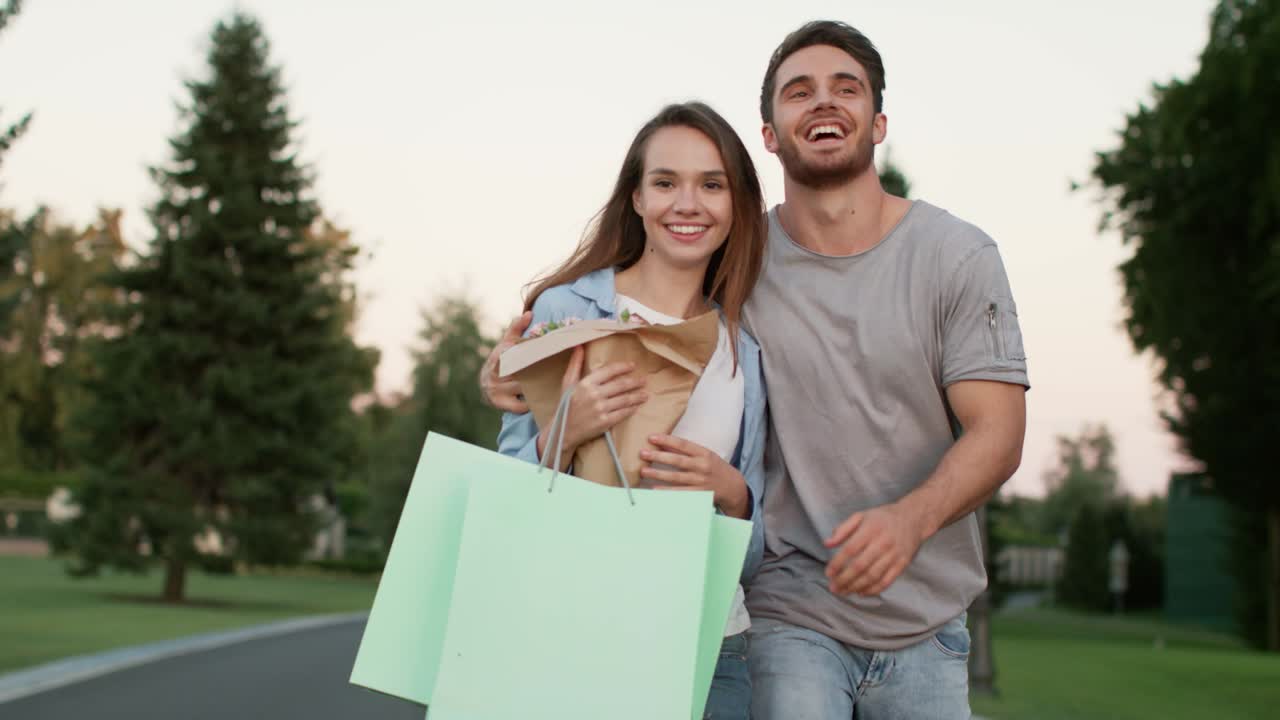 una pareja feliz caminando por la calle después de comprar. un hombre guapo abrazando a una mujer feliz.