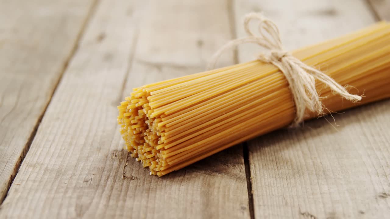 Bunch of raw spaghetti tied up with rope on wooden background