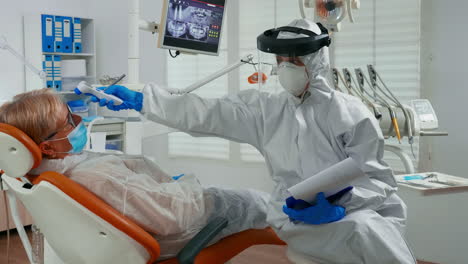 nurse with coverall using thermometer before examining patient