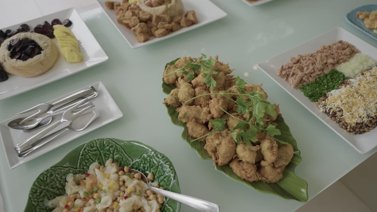 Buffet di snack fritti, insalate e piatti guarniti disposti in modo ordinato su una superficie di vetro