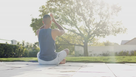 Focused-biracial-man-practicing-yoga-in-sunny-garden,-slow-motion