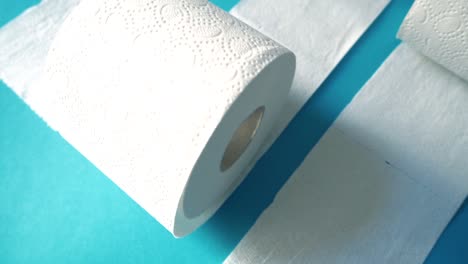 cámara lenta de varios rollos de papel higiénico contra un fondo moderno azul cian