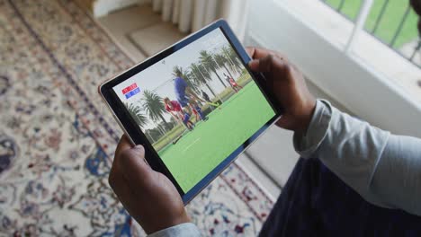 Composite-of-man-sitting-at-home,-watching-hockey-match-on-tablet