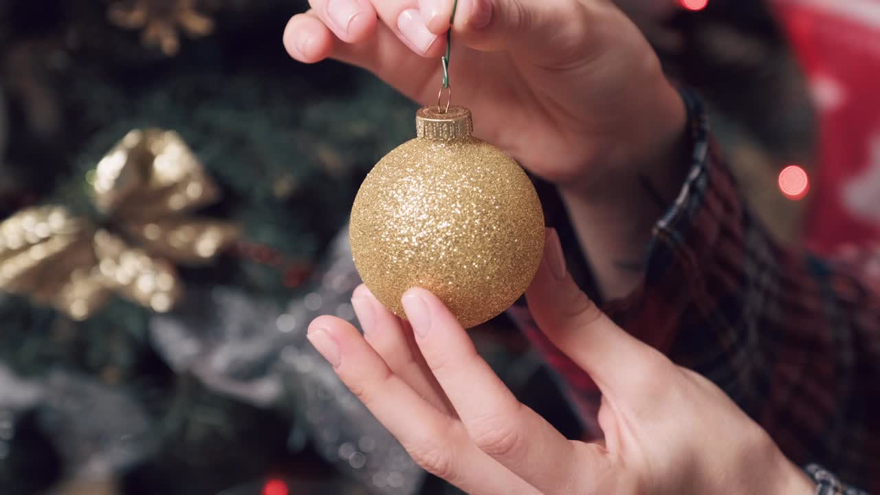 hermosa bola de navidad de color oro brillante en manos de mujeres con una manicura corta.