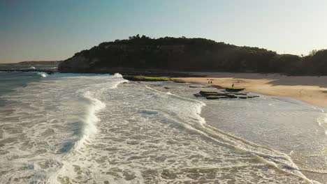 aerial view of a beach with waves and a hill