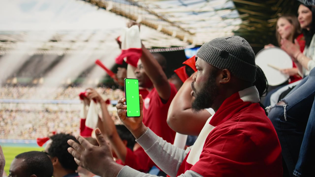 Schermo mockup verticale su un telefono tenuto da un tifoso di calcio sugli spalti dello stadio.