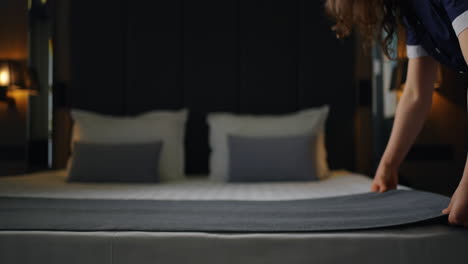 la criada haciendo una cama en una habitación de hotel