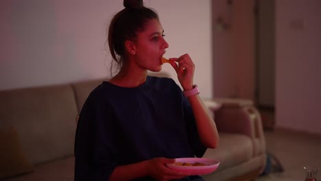 mujer comiendo papas fritas en casa