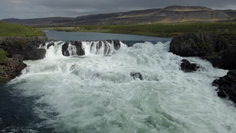 a stunning waterfall in the middle of a rugged landscape on a gloomy day in iceland