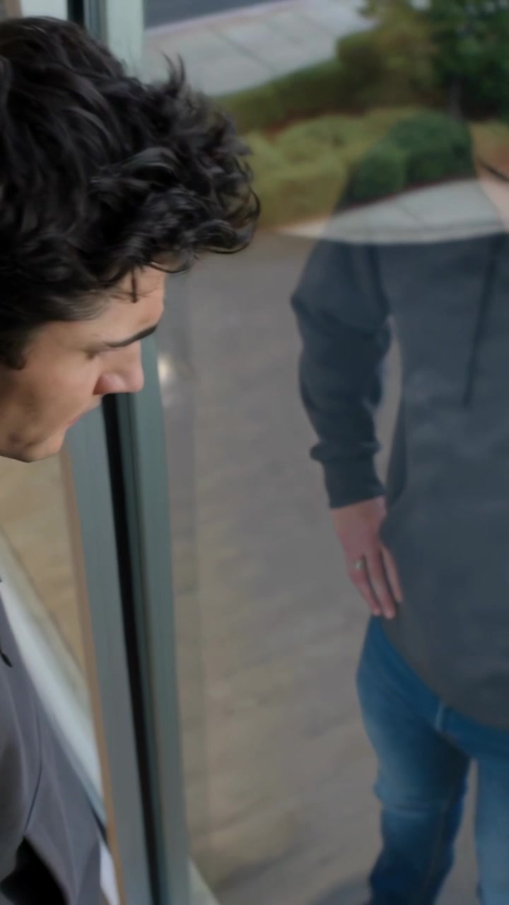 Video verticale: Telecamera panoramica che mostra un uomo in felpa grigia e jeans alla finestra che controlla un pick-up, spazio per il testo